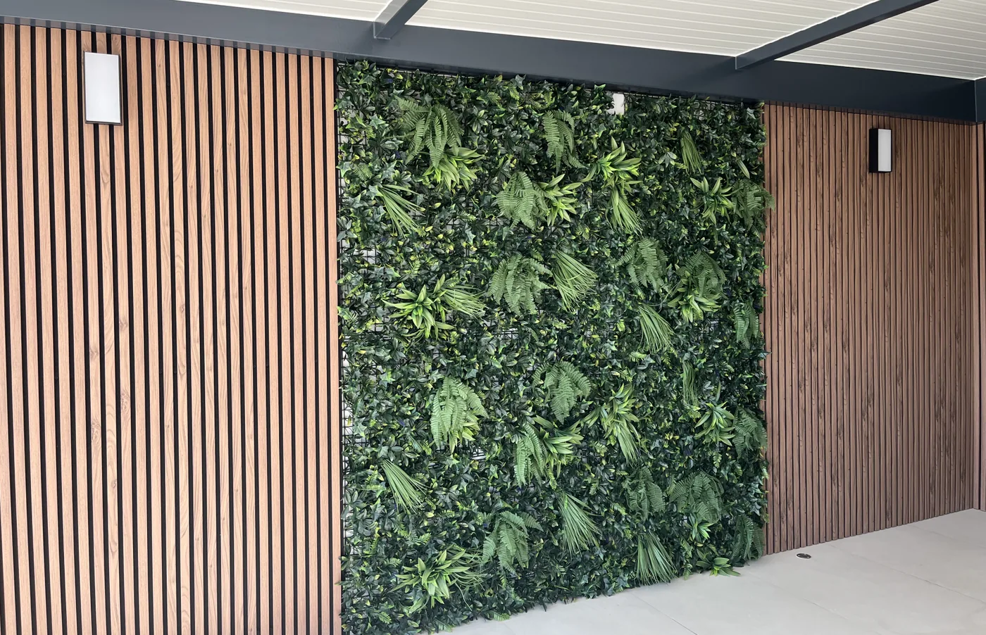 Parede do terraço com ripado de madeira dos dois lados e um painel de folhagem artificial ao centro