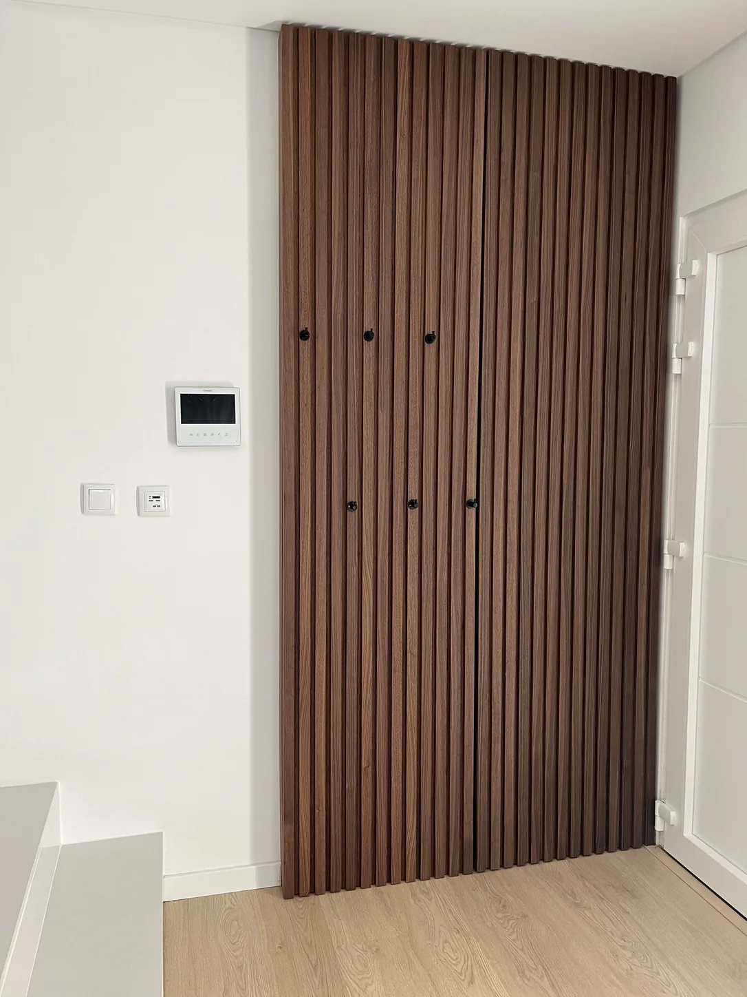 Painel de ripado em nogueira, do chão ao teto, na parede da entrada